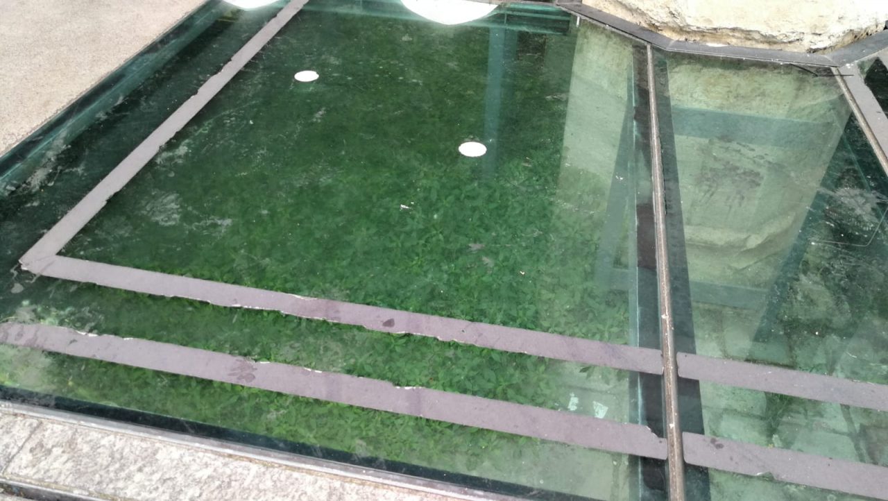 Erbacce infestanti e rifiuti sotto la passerella del Broletto. E addio pavimentazione storica FOTO