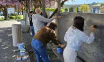 Giovani al lavoro per ripulire il muro della scuola dopo i vandalismi